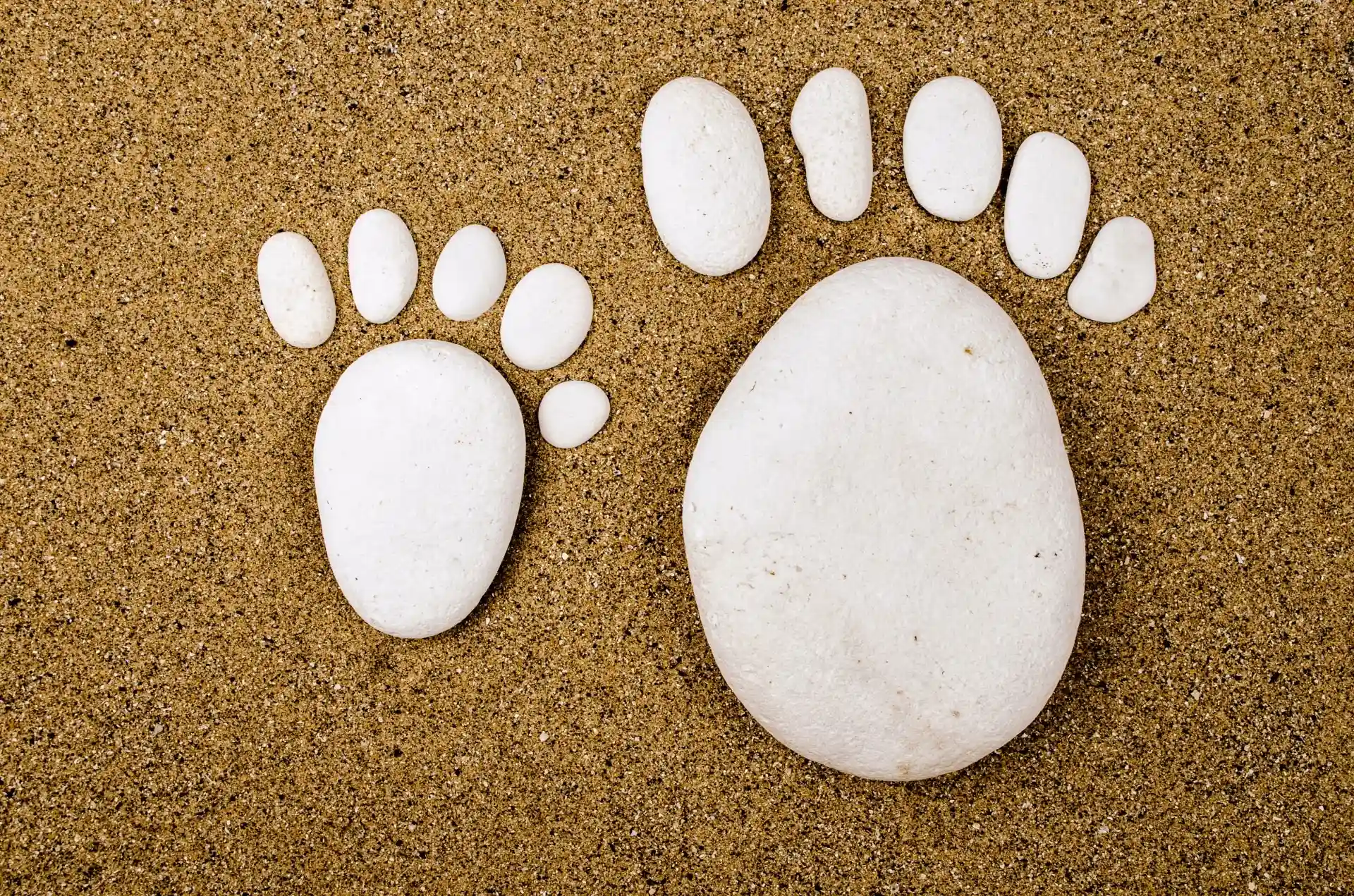 baby and adult feet made from stones laid out in sand